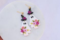 two white ghost earrings with pink flowers on them