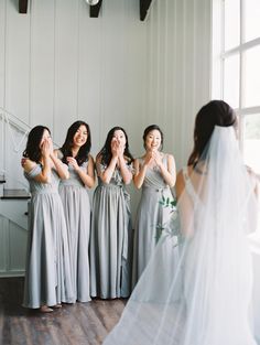 a group of women standing next to each other in front of a window with their hands together