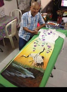 a man standing next to a table with a painting on it