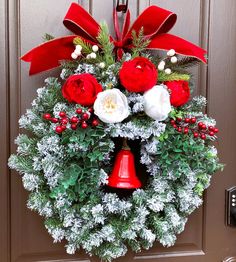 a christmas wreath with red and white flowers on it hanging from a front door handle