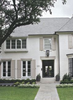 a large white house with lots of windows and plants on the front lawn in front of it