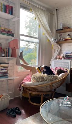 a woman laying in a hammock with her feet up on the window sill