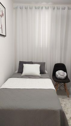 a bed sitting in a bedroom next to a window with white drapes on it