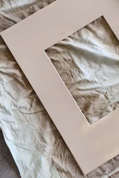 a white frame sitting on top of a bed