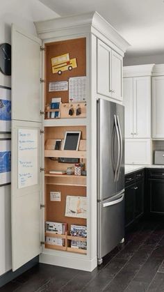 a kitchen with white cabinets and wooden shelves filled with magnets on the refrigerator door