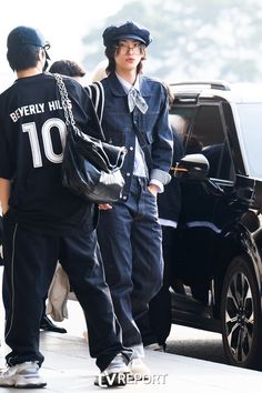 two people are walking down the street with one person carrying a handbag and another is wearing a baseball cap