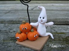 a small white figurine sitting on top of a table next to pumpkins