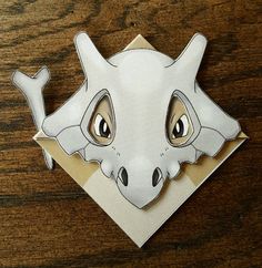 a paper cut out of a dragon head on a wooden table with wood grains