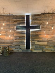 a large wooden cross sitting in the middle of a room with lights hanging from it's ceiling