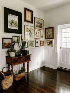 there are many framed pictures on the wall in this living room with wood flooring