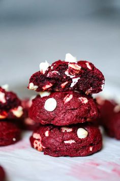 red velvet leviain cookies stacked on top of each other with white chocolate chips in the middle