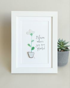 a white frame with a green plant in it and a quote written on the front