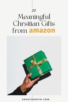 a person holding a green gift box with gold ribbon and the words, 20 meannful christian gifts from amazon