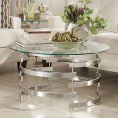 a glass table topped with a bowl of flowers on top of a hard wood floor