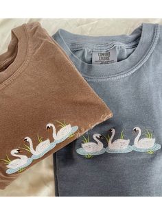 Embroidered Swan T-Shirt -Embroidered on 100% Cotton, Comfort Colors Brand T-shirts. This design is simple and minimalistic, perfect for every outfit!  -Embroidery design measures 5"x 1.5" -See product pictures for shirt sizing chart. These t-shirts run true to size, so if you like an oversized look, we recommend sizing up 1 size!  -All t-shirt designs are handmade on an embroidery machine so there may be slight differences, but we only sell the shirts that meet our high-quality standards. -To m Cotton T-shirt With Machine Embroidery, Relaxed Fit, Spring Crew Neck T-shirt With Machine Embroidery, Casual Relaxed Fit T-shirt With Machine Embroidery, Custom Embroidery Crew Neck T-shirt, Graphic Tee With Custom Embroidery Crew Neck, Reference Clothing, Alien Sweatshirt, Halloween Tee Shirts, Embroidered Sweatshirts