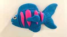 a blue and pink fish shaped cake sitting on top of a table