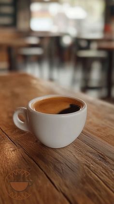 a cup of coffee sitting on top of a wooden table