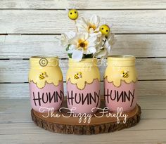 three yellow and pink painted jars with flowers in them