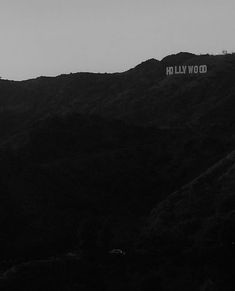 a black and white photo of the hollywood sign on top of a mountain at dusk