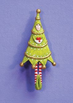 a green christmas tree hanging from the side of a purple wall with an elf's face on it