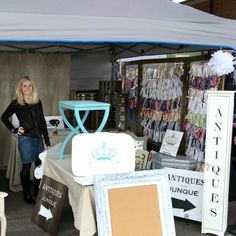 a woman standing in front of a tent selling items