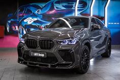 a grey bmw suv parked in front of a colorful wall with graffiti painted on it