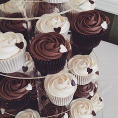 cupcakes with chocolate frosting and white hearts are arranged on a cake stand