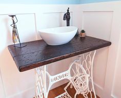 a white bowl sitting on top of a wooden table next to a sewing machine and spool