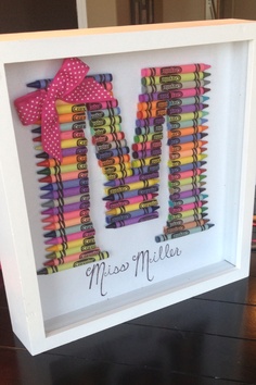 the letter m made out of crayons is displayed in a white shadow box