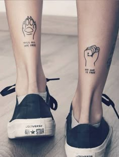 two people with tattoos on their legs and one is holding a fist up to the sky