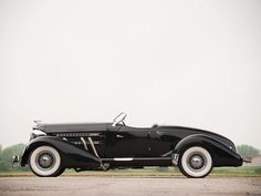 an old black car is parked on the road