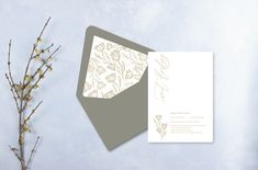 the wedding card has been designed with flowers on it and is next to a branch