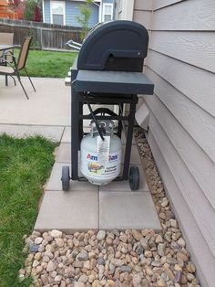 a gas tank sitting on top of a patio next to a lawn with rocks and grass