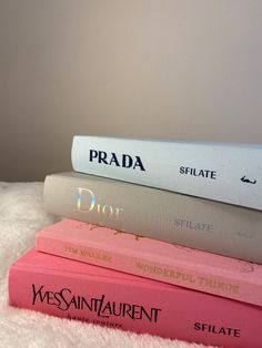 three books stacked on top of each other in front of a white bed sheet with the words prada written on them