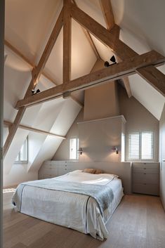 an attic bedroom with white walls and wooden beams on the ceiling, along with hardwood flooring