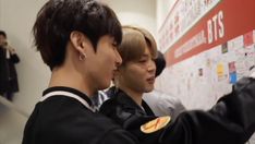 two young men standing next to each other in front of a whiteboard with stickers on it