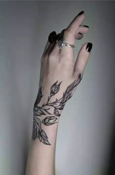 a woman's hand with black and white tattoos on her left arm, holding onto the