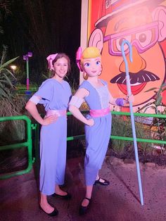 two girls in blue dresses standing next to each other near a sign that says mr and mrs potato head