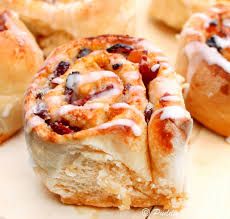 cinnamon rolls with icing sitting on a cutting board