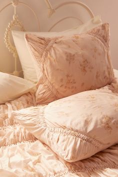 a white bed topped with lots of pillows next to a headboard and night stand