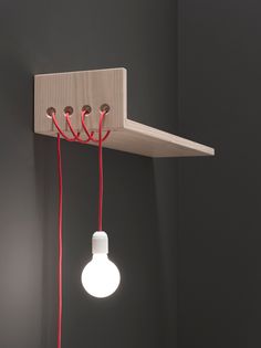 a light bulb and some wires attached to a wooden shelf in a dark room with black walls