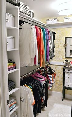 an organized closet with clothes hanging on shelves