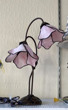 two pink stained glass flowers are sitting on a shelf next to a lamp and other items