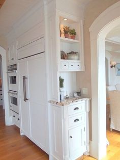 a kitchen with white cabinets and marble counter tops in an open floor plan, along with hardwood floors