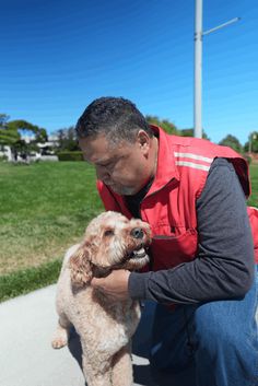 a man kneeling down petting a small dog