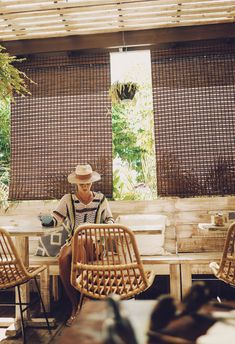 a man sitting at a table in front of two bamboo screens with windows behind him