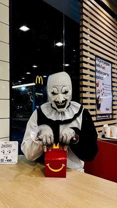 a mcdonald's employee dressed in a creepy mask and holding a hot dog box