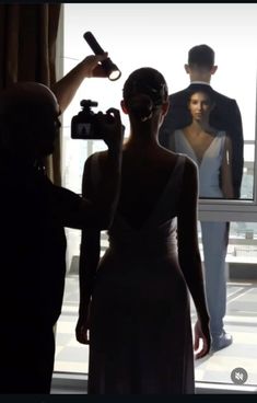 a woman in a white dress is holding a camera and taking a photo with two men standing behind her