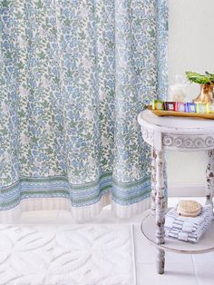 a white table sitting next to a blue and green shower curtain