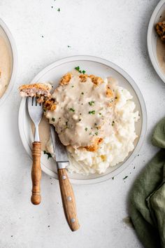 two plates with mashed potatoes and gravy on them next to a fork